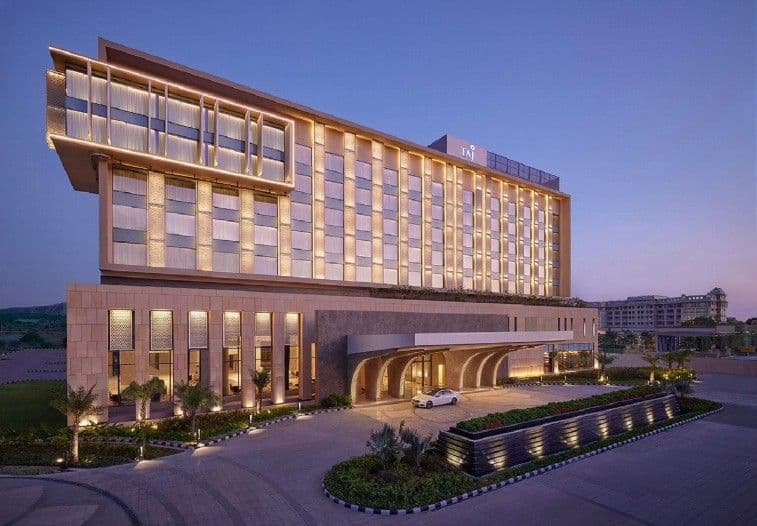 Elegant hotel building with illuminated facade and entrance driveway during evening.